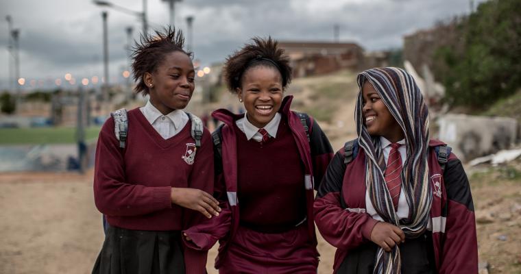 Trois filles souriantes marchent à l'école ensemble