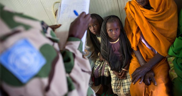 Un soldat de la paix du Nigeria enregistre une femme et deux enfants afin qu'ils puissent voir un professionnel de la santé